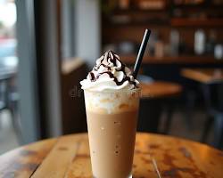Creamy iced coffee drink with whipped cream and chocolate drizzle in a café setting.